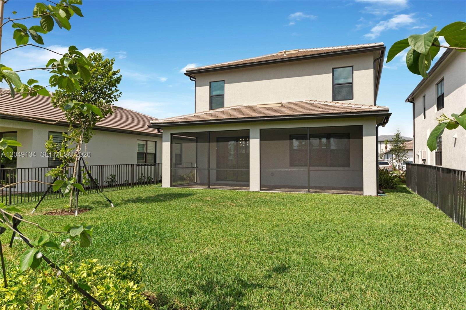 The backyard features a green lawn, a screened-in patio, and a two-story beige house — 4470 Waterside Dr, Oakland Park FL 33309, OAKLAND PARK, FL