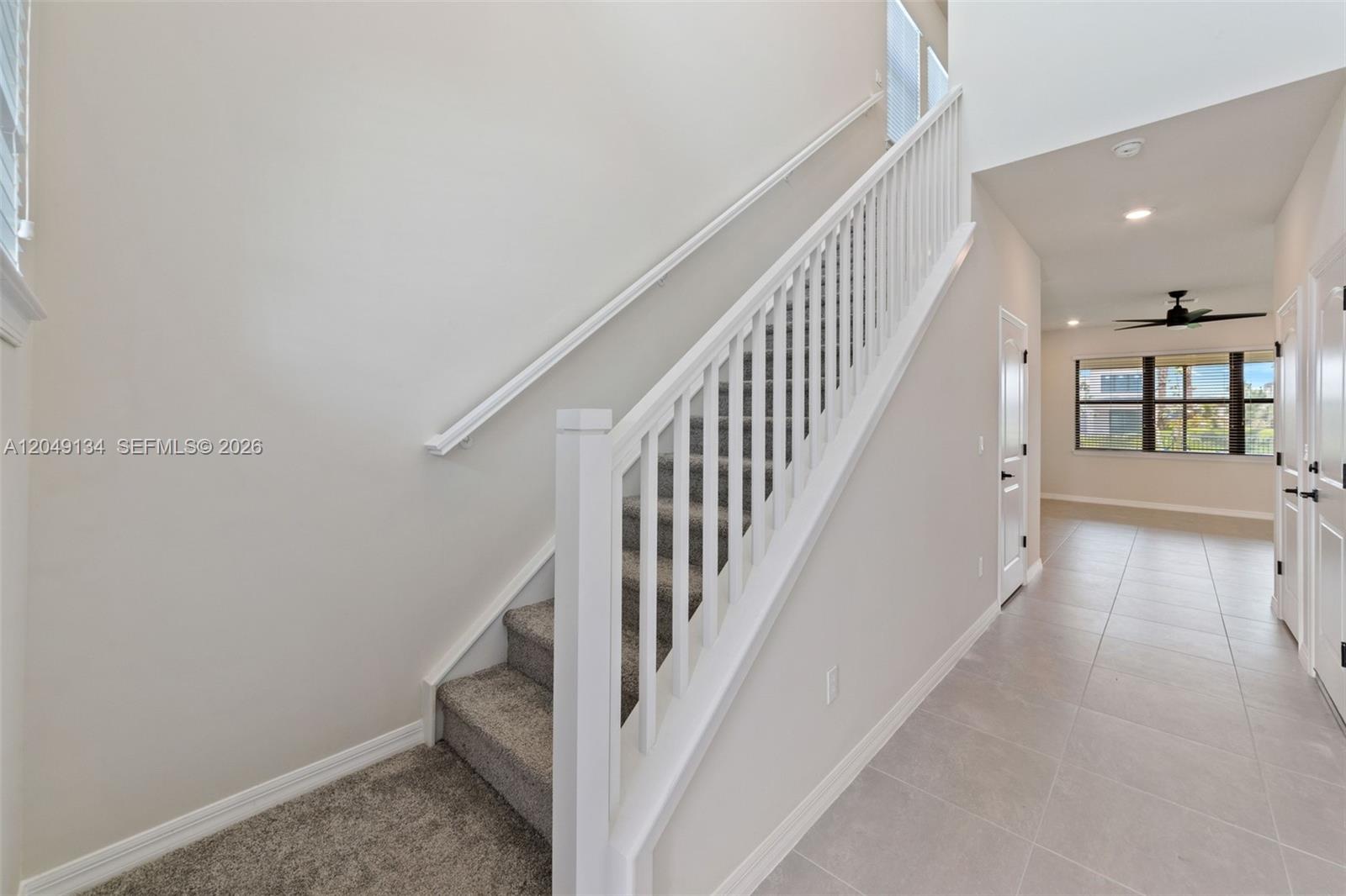 A carpeted staircase with a white railing leads to an upper level in a hallway — 4470 Waterside Dr, Oakland Park FL 33309, OAKLAND PARK, FL