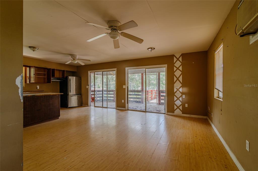 A kitchen and living area feature light wood flooring, brown walls, and sliding glass doors — 5238 NW 65TH STREET, OCALA, FL