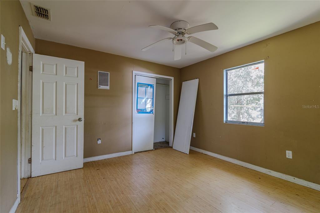 An empty bedroom features tan walls, light wood-look flooring, a ceiling fan, and a closet — 5238 NW 65TH STREET, OCALA, FL