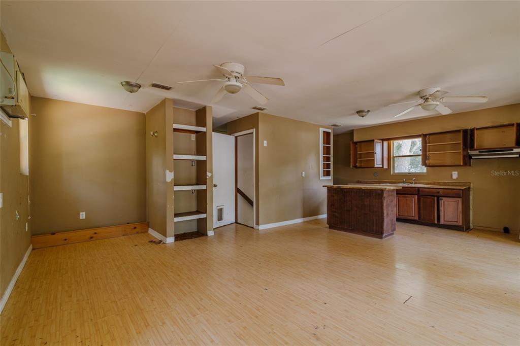 An open-concept kitchen and living area features light wood flooring, tan walls, and ceiling fans — 5238 NW 65TH STREET, OCALA, FL