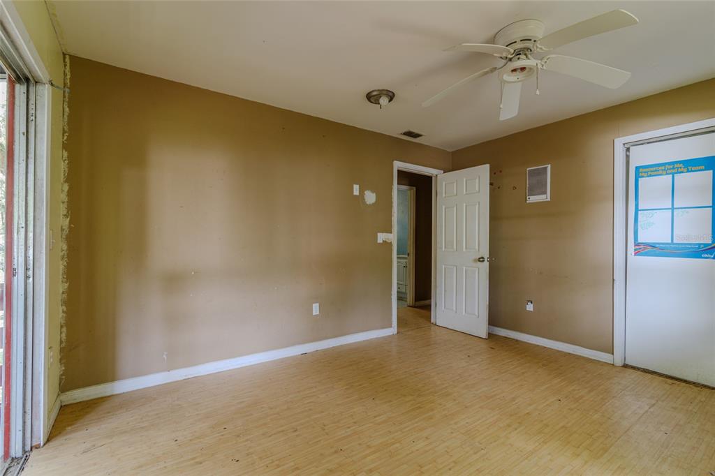 An empty room with tan walls, light wood-look flooring, a ceiling fan, and two doors — 5238 NW 65TH STREET, OCALA, FL