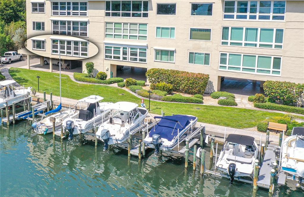 An aerial view shows beachfront multi-story residential buildings surrounded by trees and a sandy beach — 4500 GULF OF MEXICO DRIVE UNIT 206, LONGBOAT KEY, FL