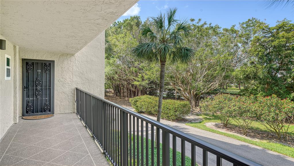 A balcony with a metal railing overlooks a paved path and lush green trees — 4500 GULF OF MEXICO DRIVE UNIT 206, LONGBOAT KEY, FL