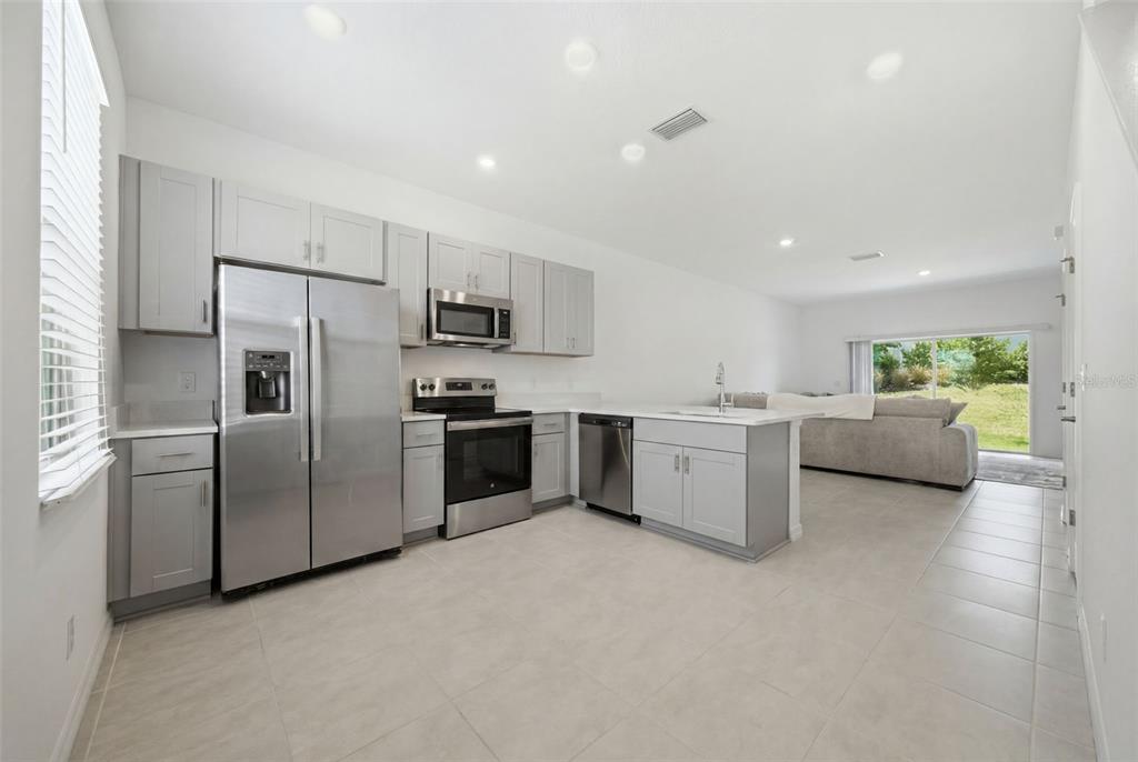A modern kitchen with light gray cabinets, stainless steel appliances, and tile flooring — 16570 SAN NICOLA PLACE, BRADENTON, FL