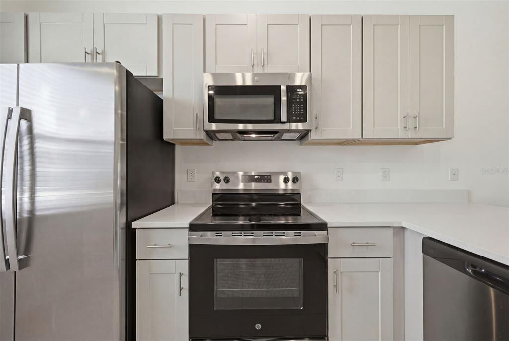 A kitchen features light gray cabinets, stainless steel appliances, and white countertops — 16570 SAN NICOLA PLACE, BRADENTON, FL