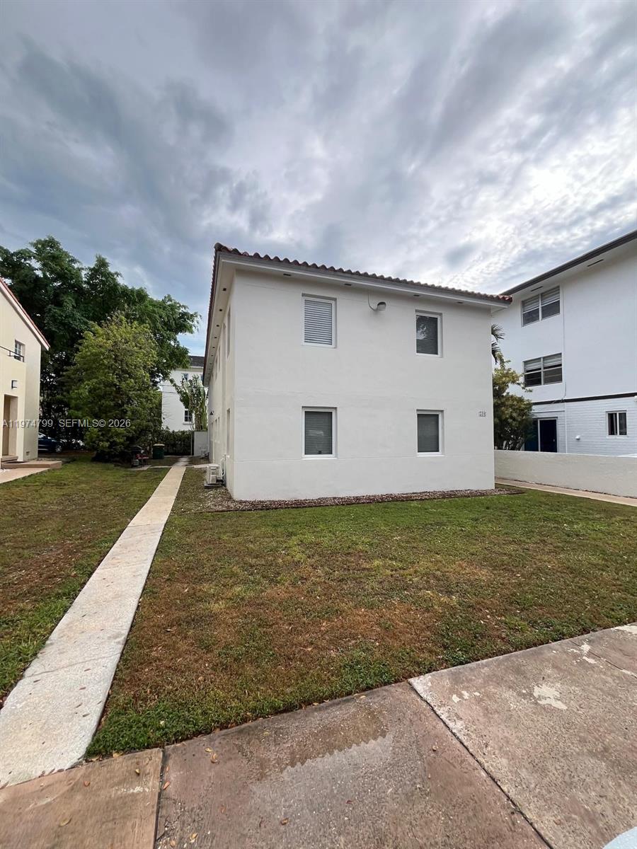The exterior of a two-story white stucco building features a lawn and concrete walkway — 510 Santander Ave # 1, Coral Gables FL 33134, CORAL GABLES, FL