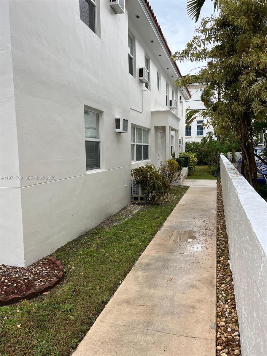 A white multi-story building exterior features a concrete walkway alongside a low stone wall — 510 Santander Ave # 1, Coral Gables FL 33134, CORAL GABLES, FL