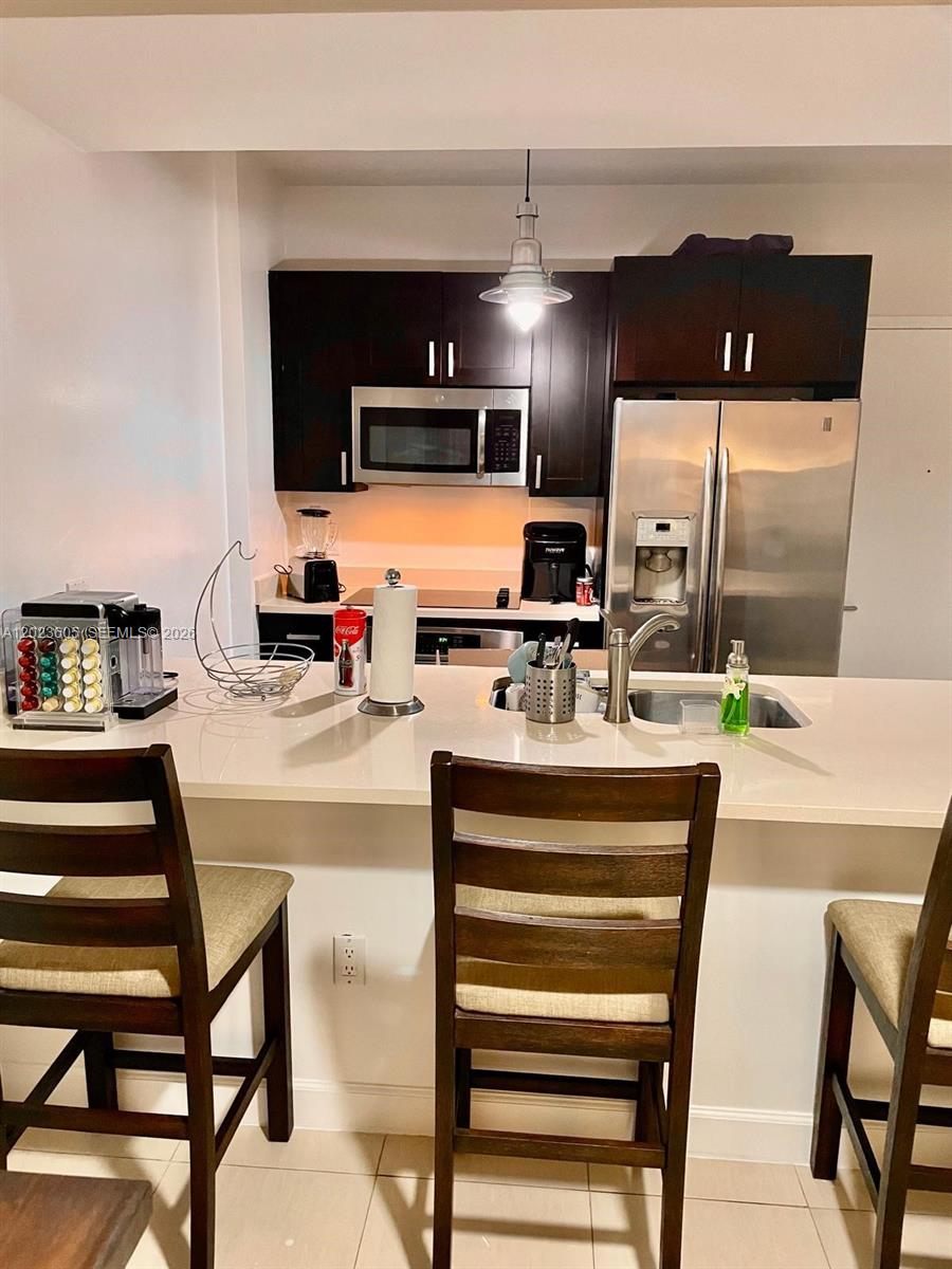 A kitchen features dark wood cabinets, stainless steel appliances, and a white breakfast bar — 333 NE 24th St # 1108, Miami FL 33137, MIAMI, FL