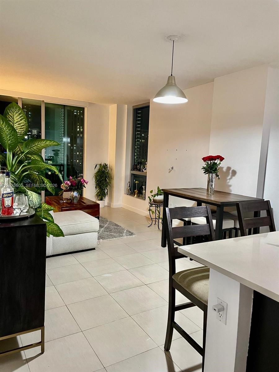A modern apartment living and dining area features tile flooring, a pendant light, and floor-to-ceiling windows — 333 NE 24th St # 1108, Miami FL 33137, MIAMI, FL