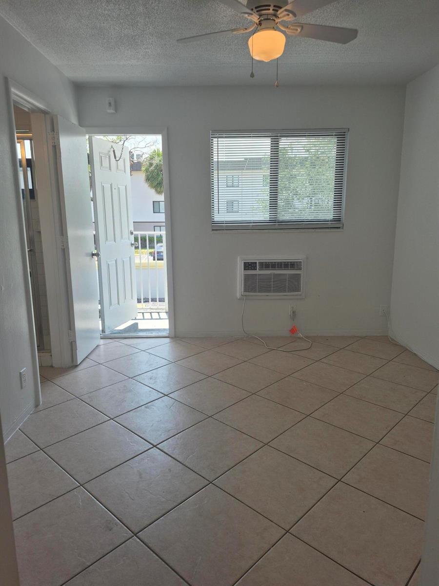 A room with tiled floors, a ceiling fan, a window air conditioner, and an open door — 1960 NE 48 Street # 9, Pompano Beach FL 33064, POMPANO BEACH, FL