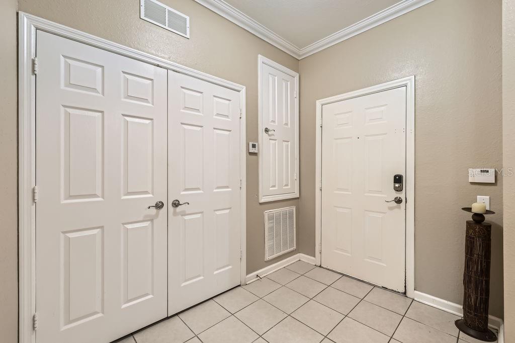 An entryway with tiled flooring, a white double-door closet, and a white front door — 6434 CAVA ALTA DRIVE UNIT 210, ORLANDO, FL
