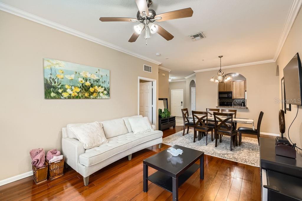 A living and dining area with hardwood floors, a white sofa, and a ceiling fan — 6434 CAVA ALTA DRIVE UNIT 210, ORLANDO, FL