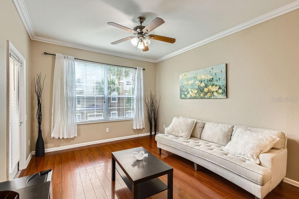 A living room features a beige sofa, a dark coffee table, and hardwood floors — 6434 CAVA ALTA DRIVE UNIT 210, ORLANDO, FL