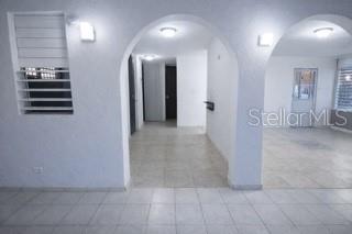 An interior view shows a tiled room with arched doorways leading to other living spaces — C-8 RAUL DE JESÚS, JUNCOS, PR