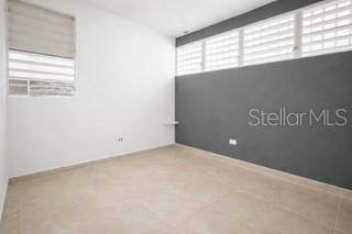 An empty room features white walls, a gray accent wall, and light-colored tile flooring — C-8 RAUL DE JESÚS, JUNCOS, PR