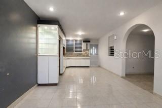 An open-concept room features light tile flooring, a dark accent wall, and a white kitchen — C-8 RAUL DE JESÚS, JUNCOS, PR