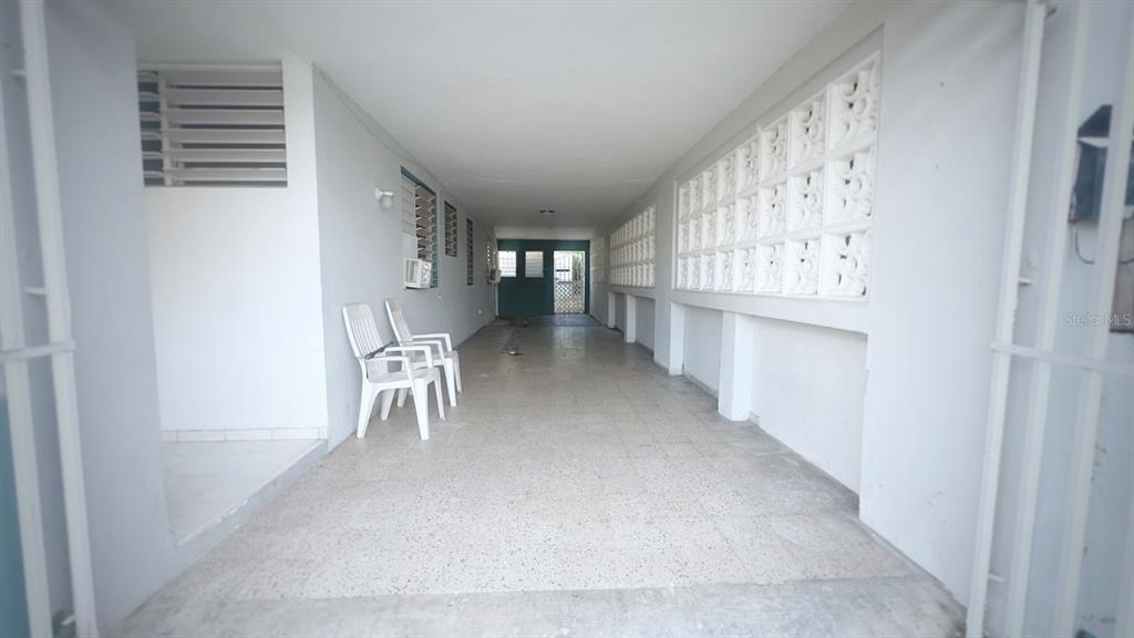A long, covered outdoor carport or patio with white walls and a tiled floor — C-8 RAUL DE JESÚS, JUNCOS, PR