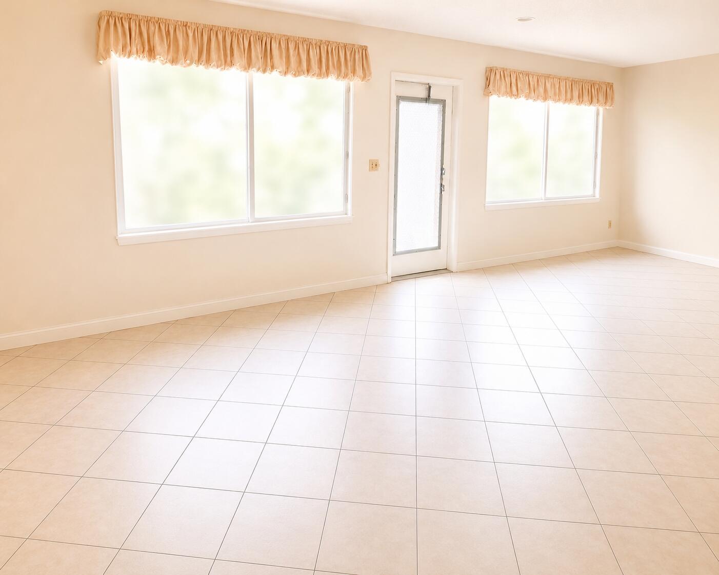An empty room with beige tile flooring, light-colored walls, two windows with valances, and a door — 1015 Ainslie A Drive, Boca Raton FL 33434, BOCA RATON, FL
