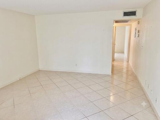 An empty room with light-colored tile flooring and a doorway leading to a hallway — 1015 Ainslie A Drive, Boca Raton FL 33434, BOCA RATON, FL