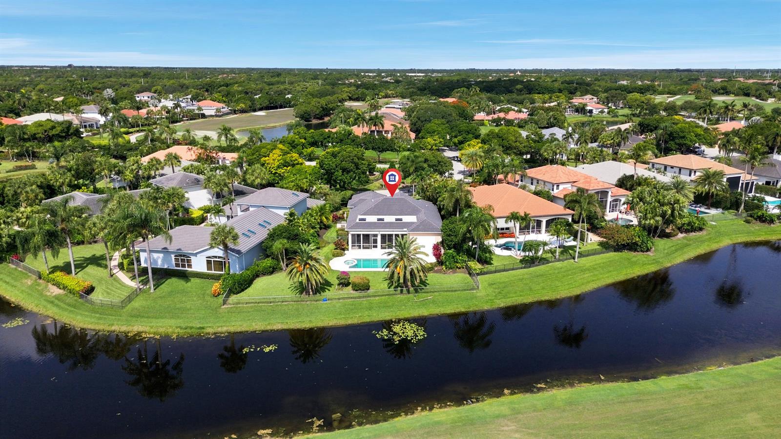 An aerial view shows a residential house with a pool and patio beside a lake — 173 N Village Way, Jupiter FL 33458, JUPITER, FL