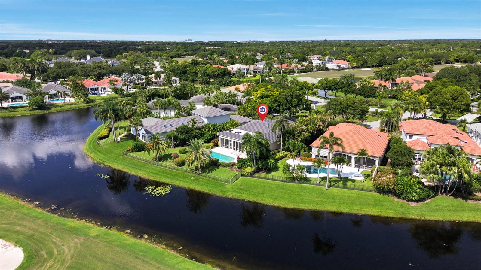 An aerial view shows a residential neighborhood with houses, swimming pools, and a lake — 173 N Village Way, Jupiter FL 33458, JUPITER, FL