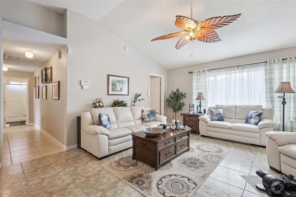 A living room features tile flooring, white leather sofas, a wooden coffee table, and a fan — 2563 SHEFFIELD DRIVE, DELTONA, FL
