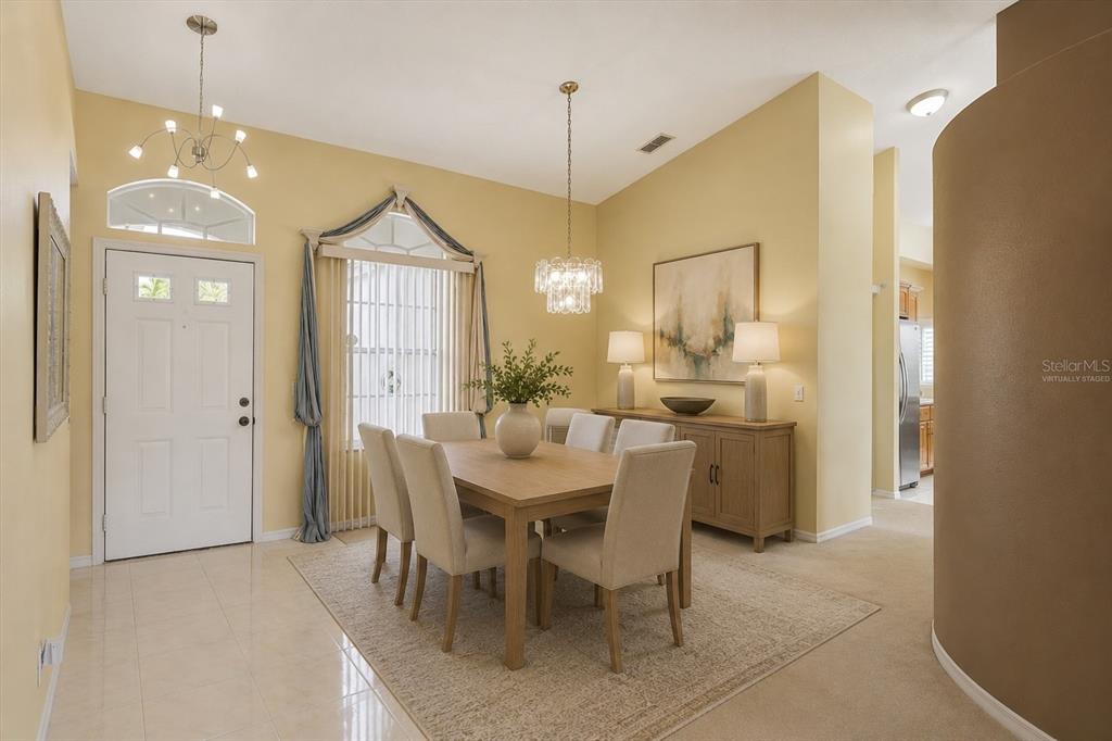 A dining room features a wooden table, upholstered chairs, a chandelier, and yellow walls — 5157 39TH STREET W, BRADENTON, FL