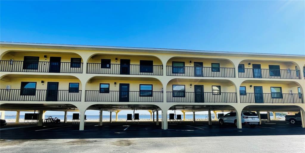 The exterior of a multi-story apartment building features arched supports and covered ground-level parking — 14459 RIVER BEACH DRIVE UNIT C122, PORT CHARLOTTE, FL