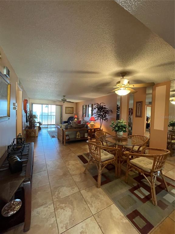 An open-concept living and dining area features tile flooring, a ceiling fan, and balcony access — 14459 RIVER BEACH DRIVE UNIT C122, PORT CHARLOTTE, FL