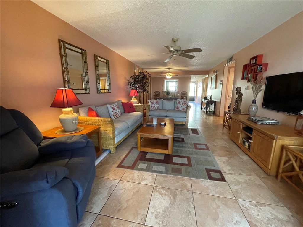 A living room features tile flooring, wicker sofas, a coffee table, and a television console — 14459 RIVER BEACH DRIVE UNIT C122, PORT CHARLOTTE, FL