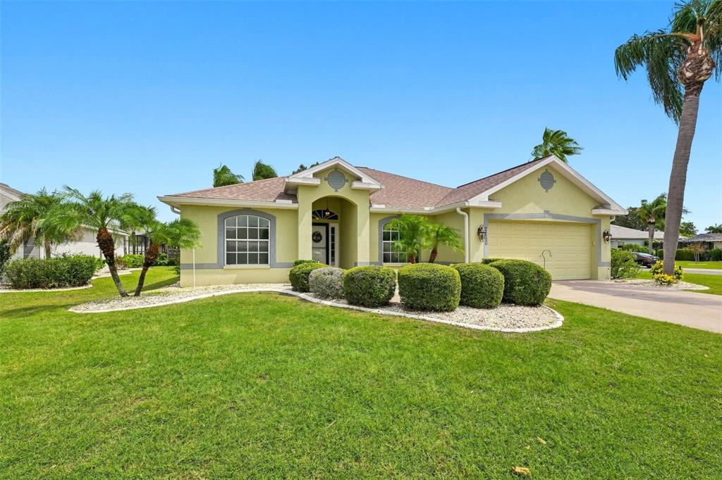 A single-story house with a yellow exterior, a two-car garage, and a manicured front lawn — 2242 W DEL WEBB BOULEVARD, SUN CITY CENTER, FL