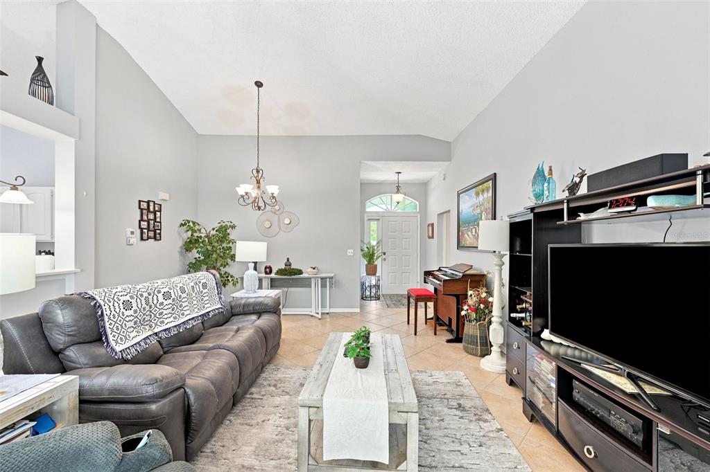 A living room features a gray leather sofa, a wooden coffee table, and a television console — 2242 W DEL WEBB BOULEVARD, SUN CITY CENTER, FL