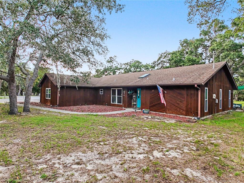A single-story house with brown wood siding, a shingled roof, and a turquoise front door — 5253 W ROCHELLE STREET, HOMOSASSA, FL