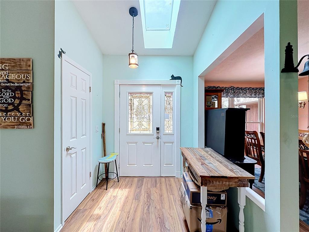 An entryway features wood-look flooring, a skylight, a white front door, and a wooden console table — 5253 W ROCHELLE STREET, HOMOSASSA, FL