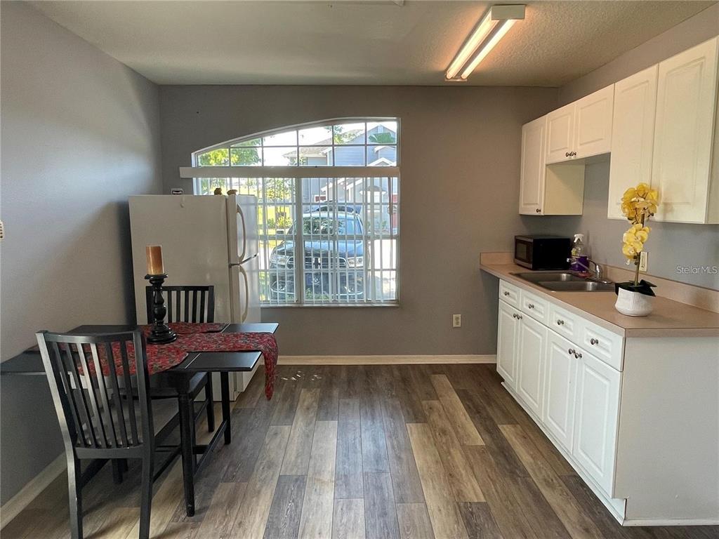 A kitchen with white cabinets, wood-look flooring, a dining table, and a large window — 272 COCO PLUM DRIVE, DAVENPORT, FL