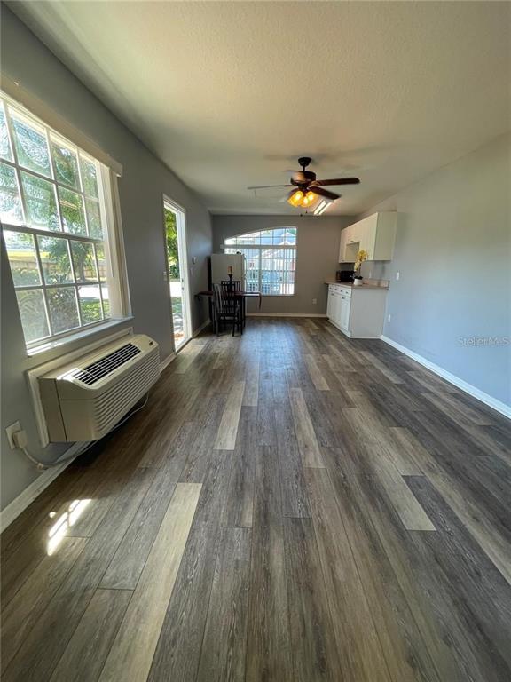 A room with wood-look flooring, a ceiling fan, a window unit air conditioner, and kitchen cabinets — 272 COCO PLUM DRIVE, DAVENPORT, FL