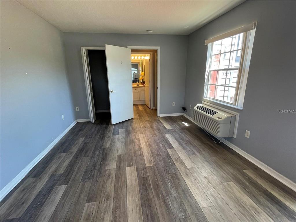 A bedroom with gray walls, wood-look flooring, a window air conditioner, and an attached bathroom — 272 COCO PLUM DRIVE, DAVENPORT, FL