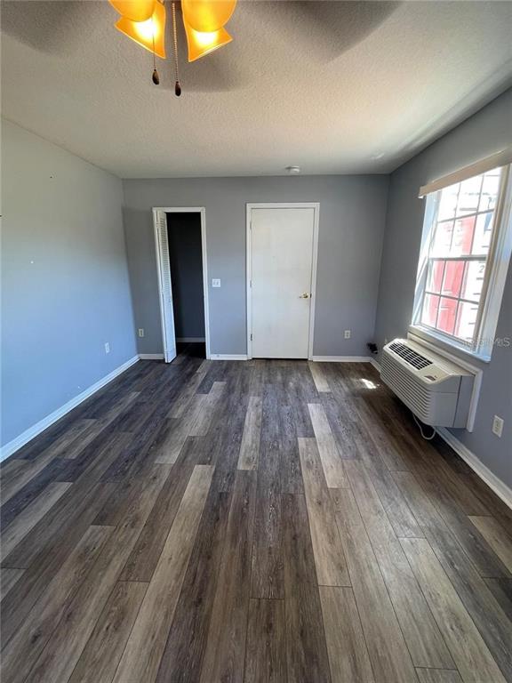 A bedroom features gray walls, wood-look plank flooring, a ceiling fan, and a wall-mounted air conditioner — 272 COCO PLUM DRIVE, DAVENPORT, FL