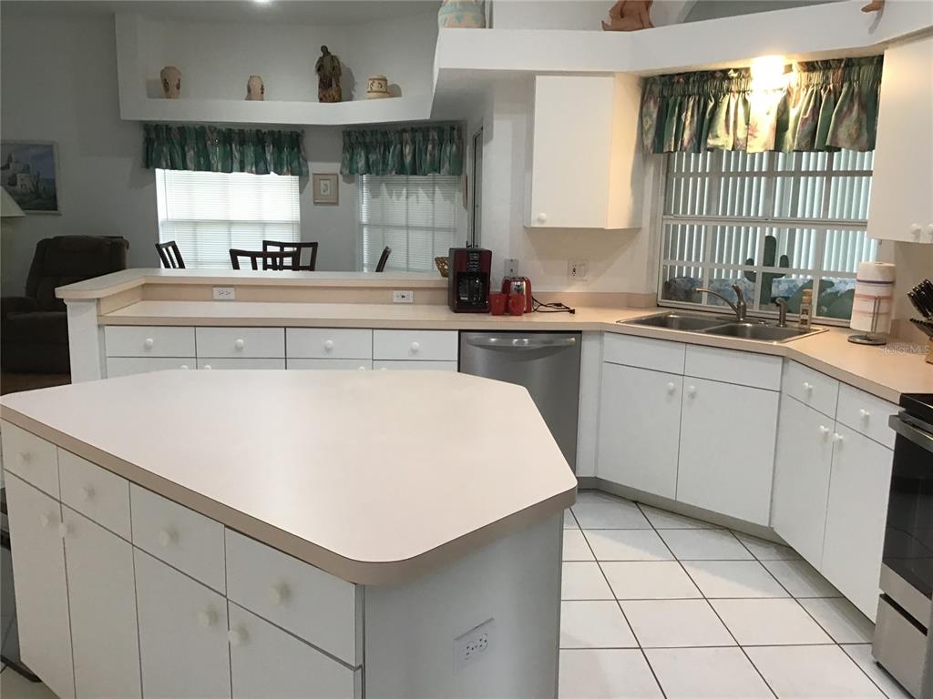 A kitchen features white cabinets, a large central island, and a double sink under windows — 2984 TUSKET AVENUE, NORTH PORT, FL