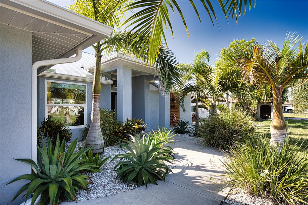 A concrete walkway leads to the entrance of a light blue house with palm trees — 815 ACADIA ROAD, VENICE, FL