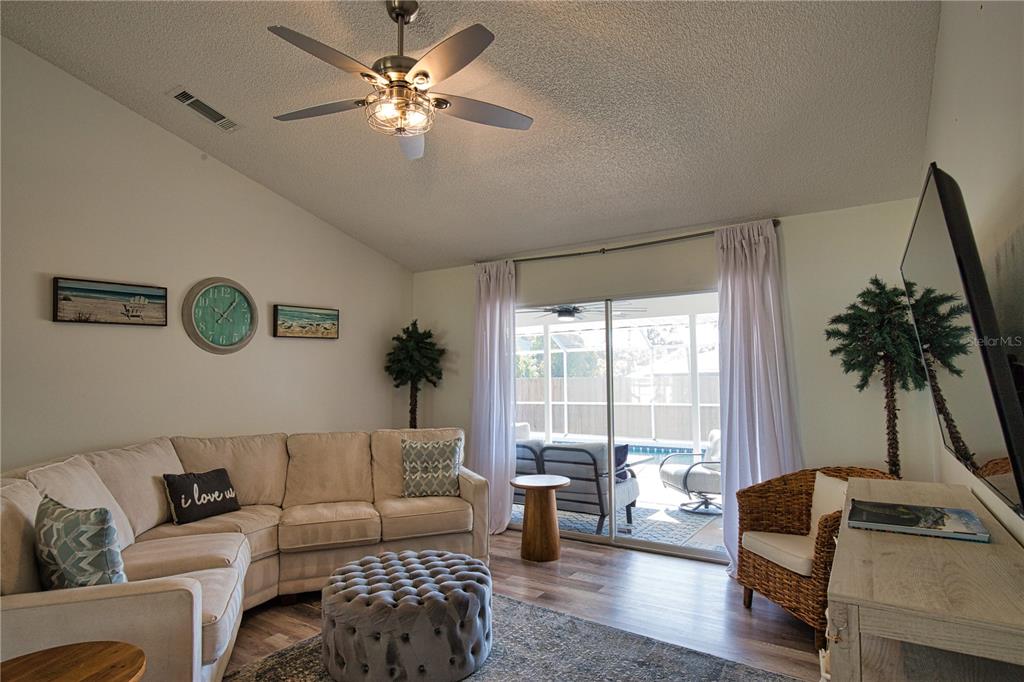 A living room features a sectional sofa, a tufted ottoman, and sliding doors to a patio — 815 ACADIA ROAD, VENICE, FL