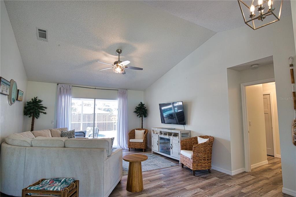 A living room features a sectional sofa, wicker chairs, a television, and wood-look flooring — 815 ACADIA ROAD, VENICE, FL