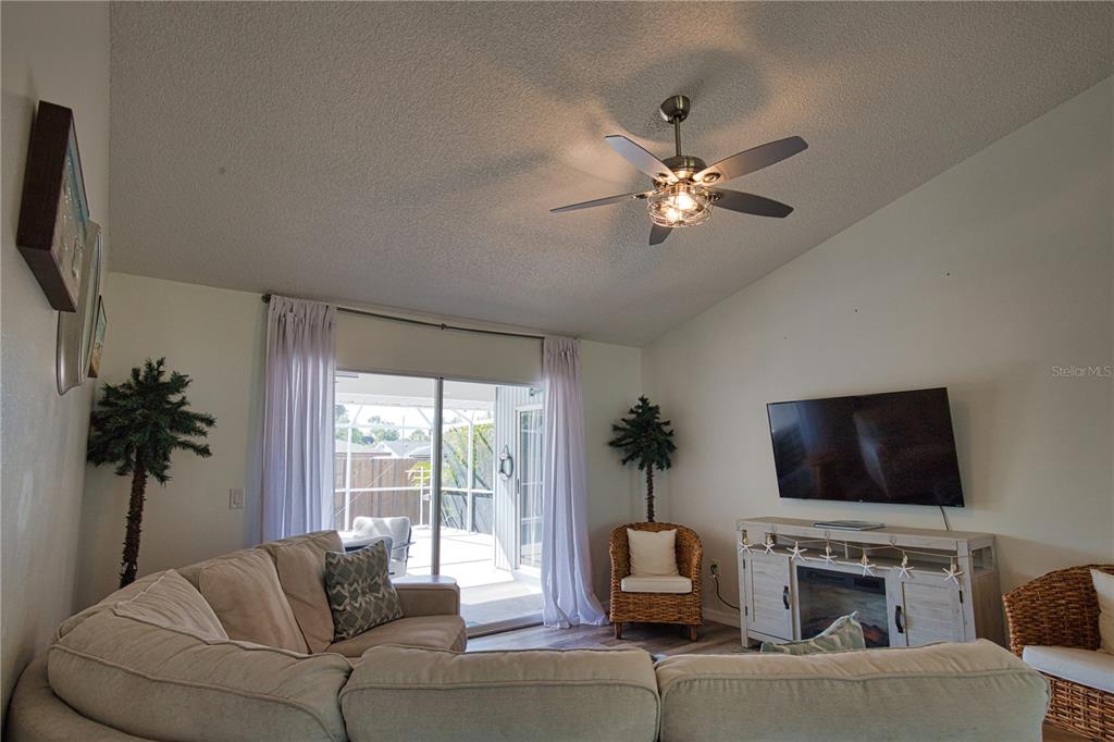 A living room features a sectional sofa, a television, a ceiling fan, and sliding doors — 815 ACADIA ROAD, VENICE, FL