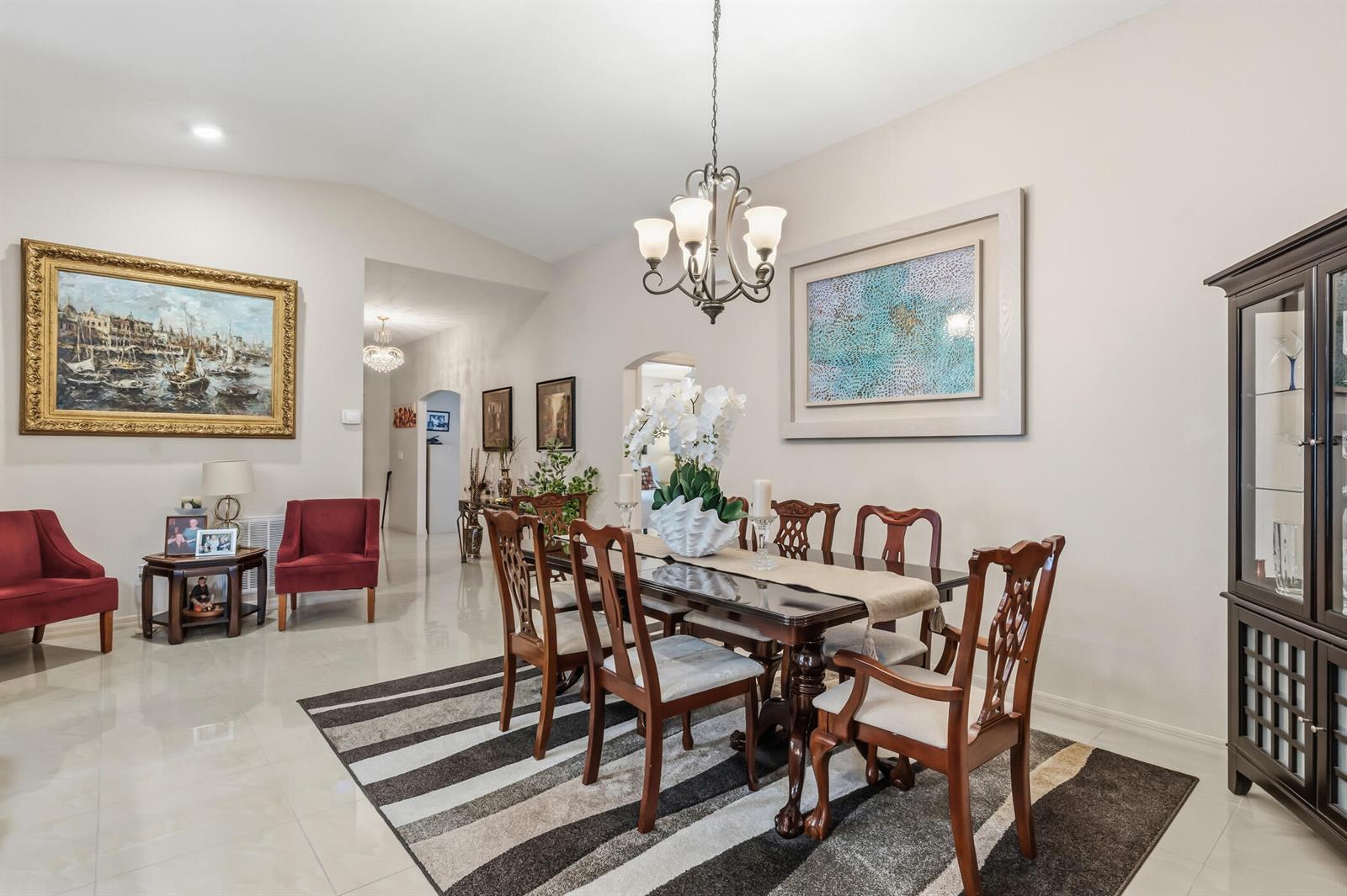 A dining room features a dark wood table, six chairs, a chandelier, and a striped rug — 1013 E 13th Square, Vero Beach FL 32960, VERO BEACH, FL