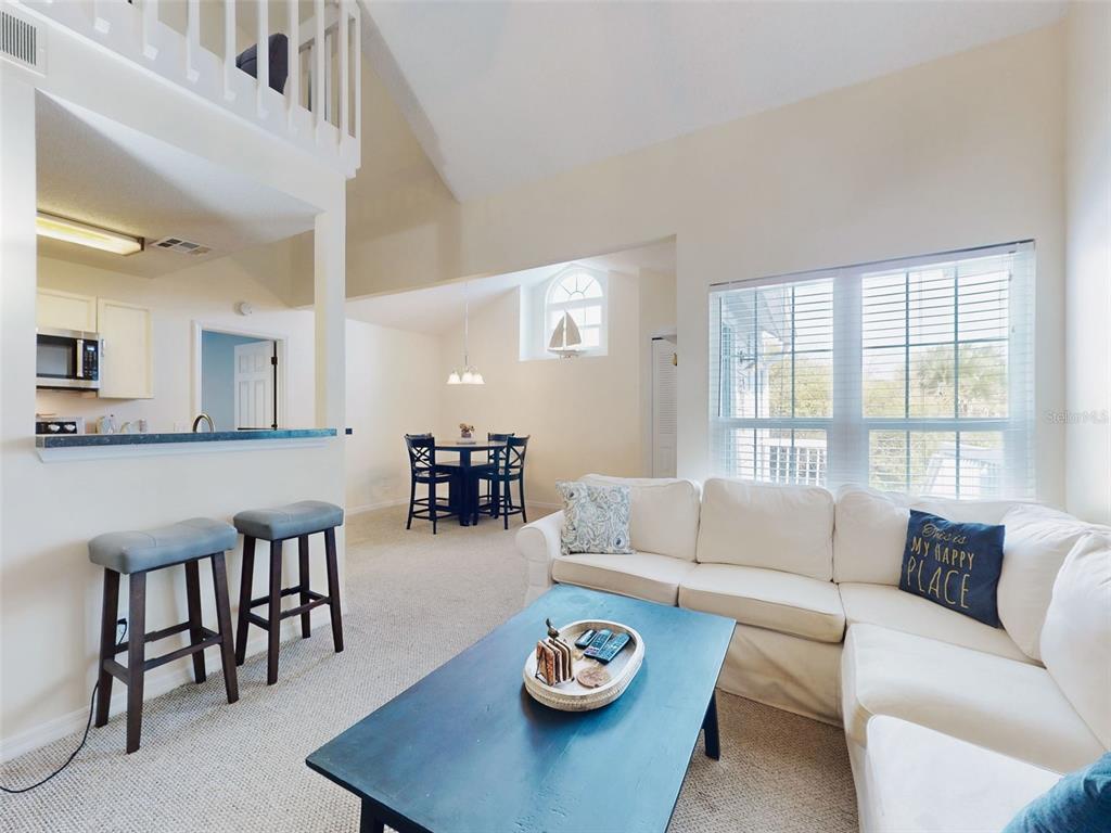 A living room with a sectional sofa, coffee table, and an adjacent dining area — 4214 SUN VILLAGE COURT UNIT 380, NEW SMYRNA BEACH, FL