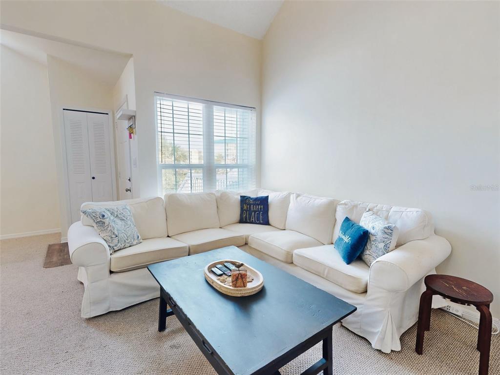 A living room features a white sectional sofa, a black coffee table, and a window — 4214 SUN VILLAGE COURT UNIT 380, NEW SMYRNA BEACH, FL
