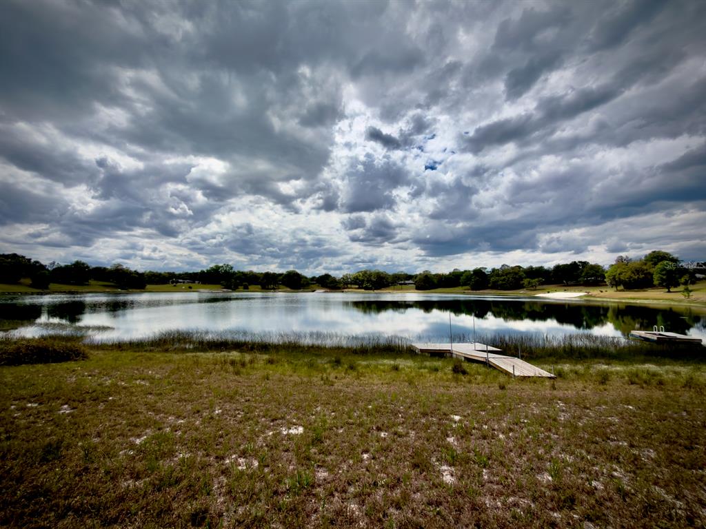 A wooden dock extends into a calm lake under a cloudy sky — 00 SE 146TH TERRACE ROAD, OCKLAWAHA, FL