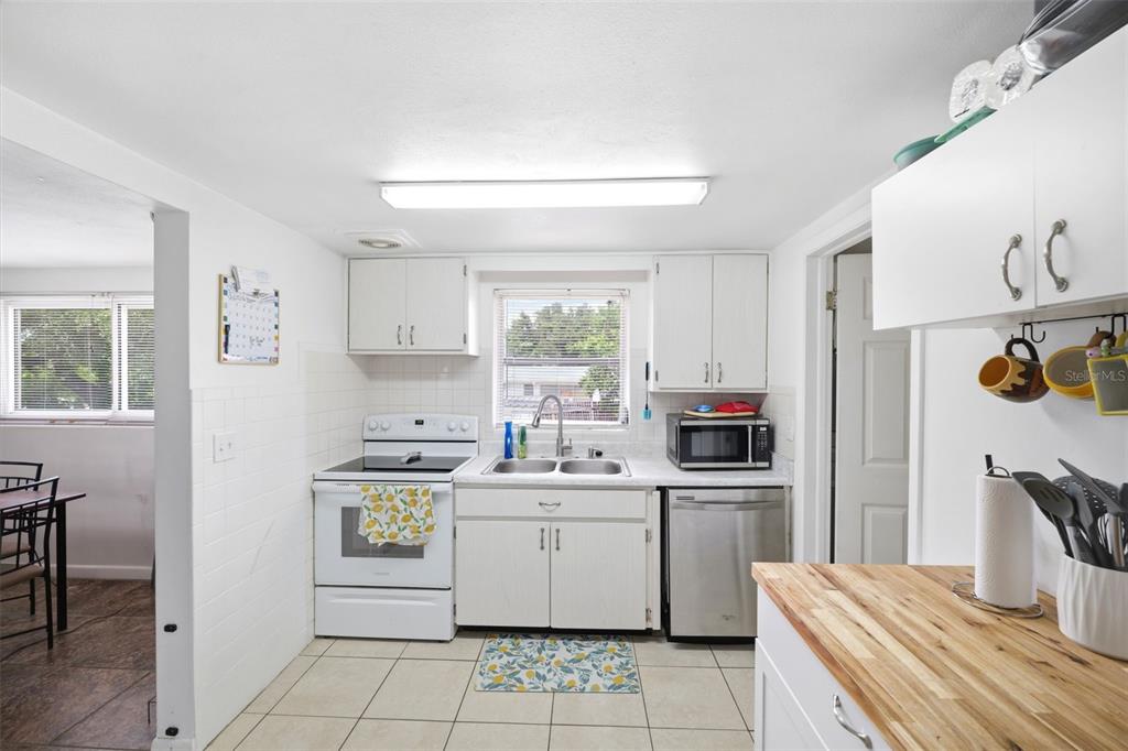 A kitchen features white cabinetry, stainless steel appliances, a tile floor, and a butcher block countertop — 13 E LEMON STREET, BEVERLY HILLS, FL