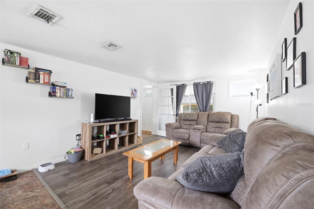 A living room with wood-look flooring, a television on a cubby stand, and two sofas — 13 E LEMON STREET, BEVERLY HILLS, FL